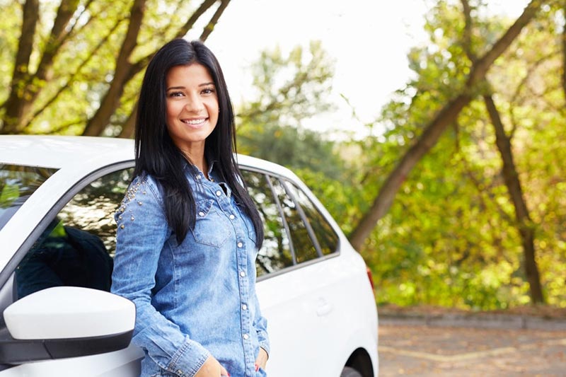 Young happy woman standing by her car in recreational travel trip