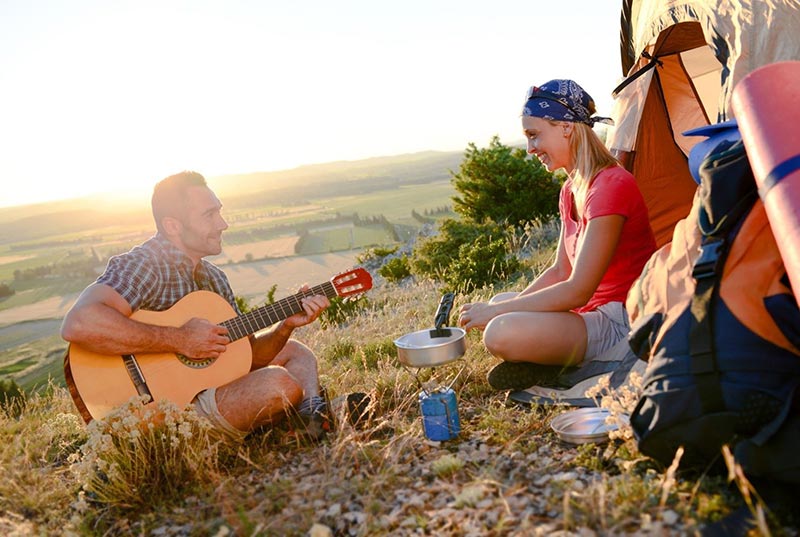 Young-couple-playing-guitar-in-summer-tent-camp